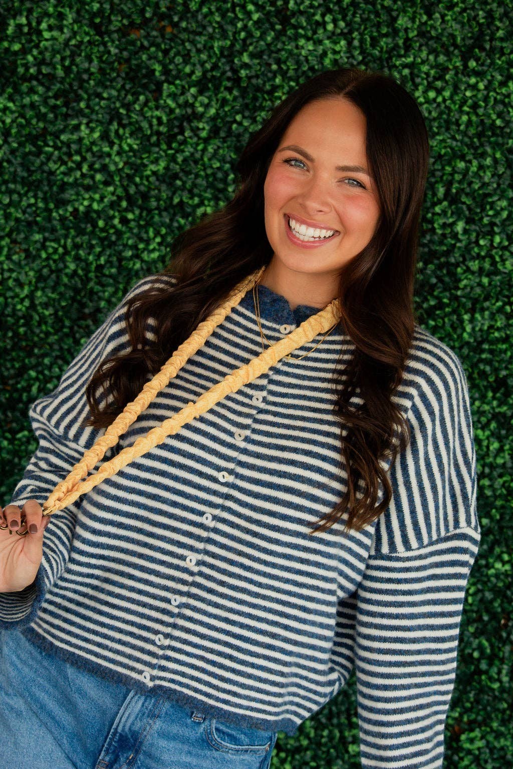 Doodlations Coffee Bar & Boutique Bloom yellow floral linen lanyard worn by a smiling woman against a green wall