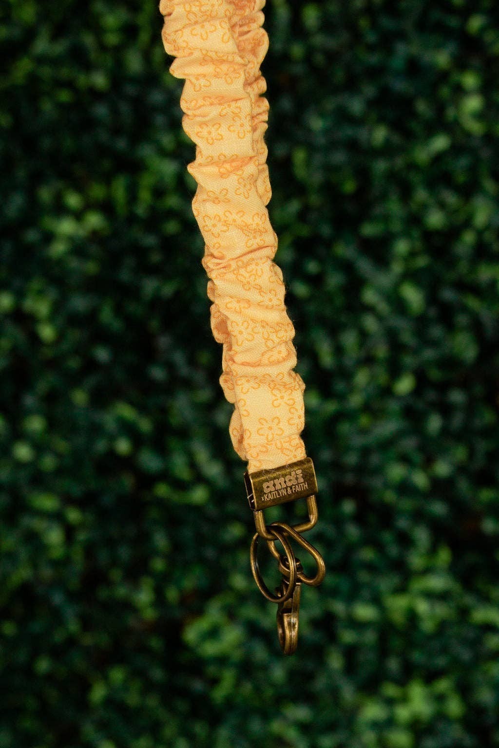 Doodlations Coffee Bar & Boutique Bloom lanyard in yellow linen fabric with a dainty floral print and gold hardware.