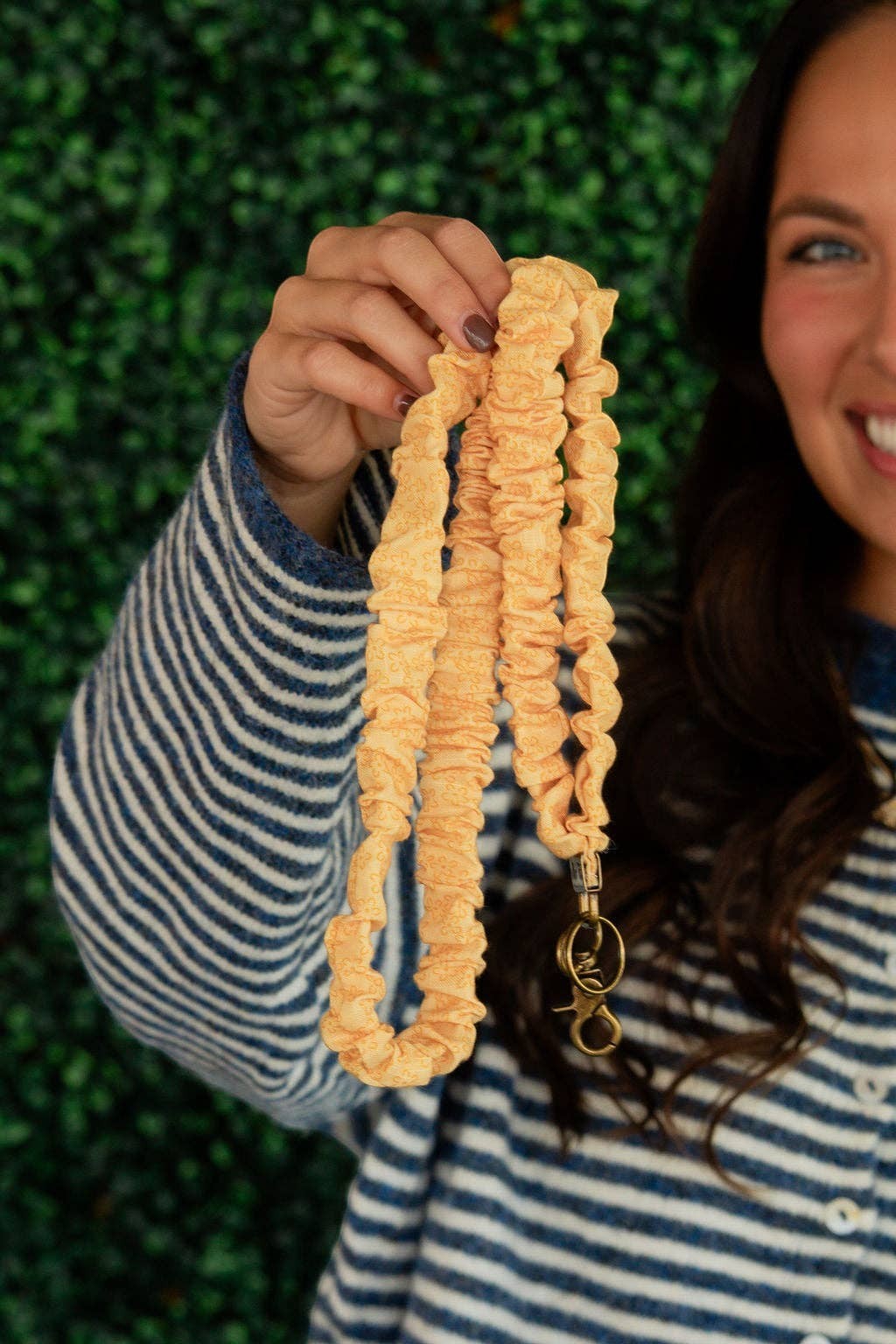 Doodlations Coffee Bar & Boutique Bloom lanyard in yellow floral print linen fabric held by a smiling woman