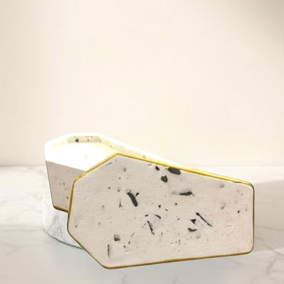 Doodlations Concrete Candle in a white casket vessel with gold trim and black speckles. Dual-wick candle.