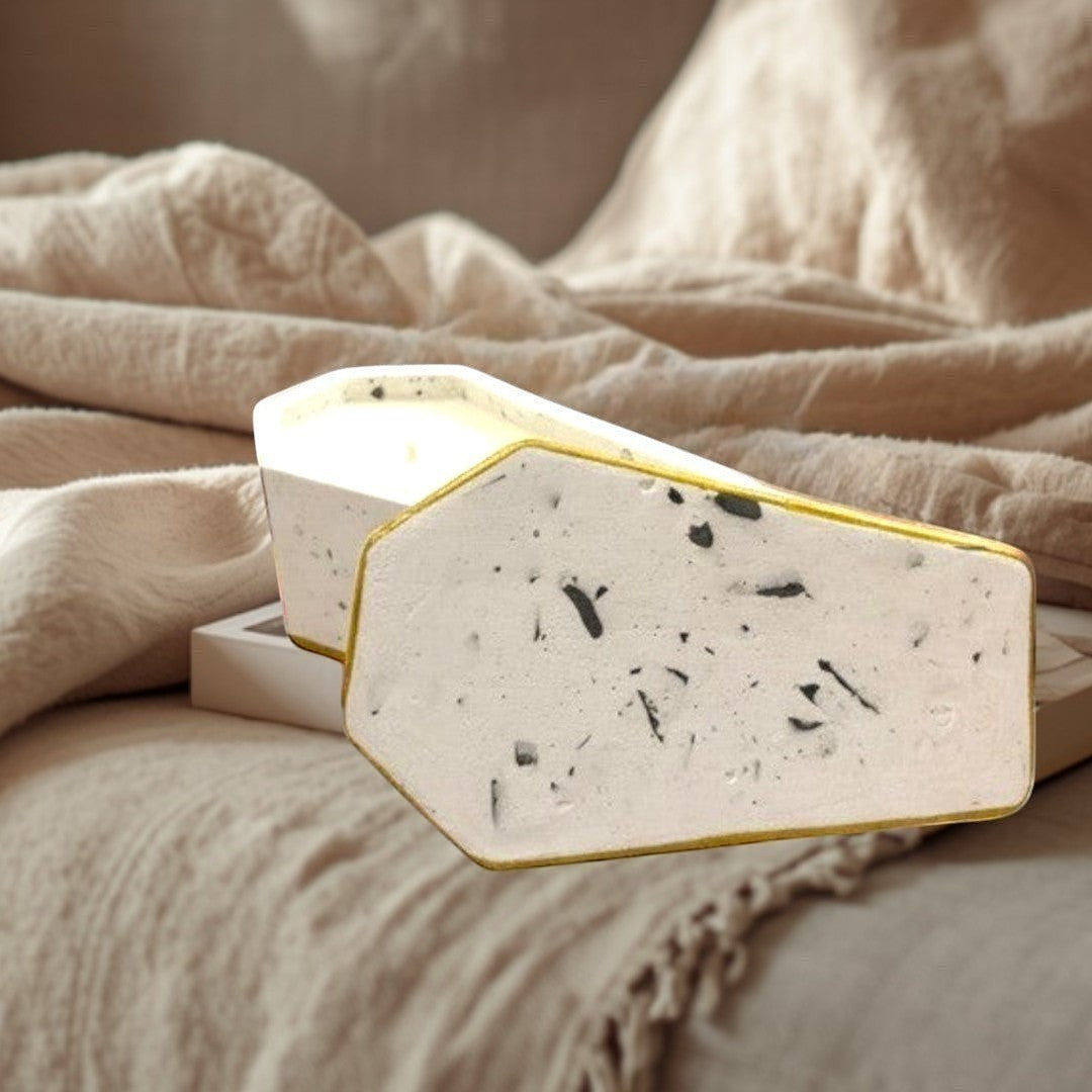 Doodlations Concrete Candle in a white casket vessel with gold trim and black speckles. Two wicks.