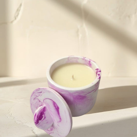 Doodlations Coffee Bar & Boutique white concrete candle with pink marbling and lid. Cream-colored wax.