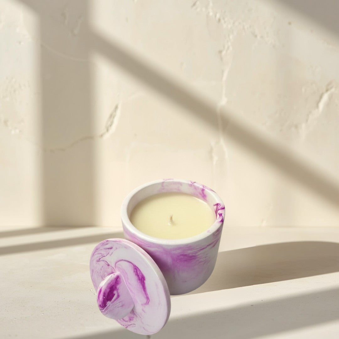 Doodlations Coffee Bar & Boutique white concrete candle with pink marbling and lid. Cream-colored wax.