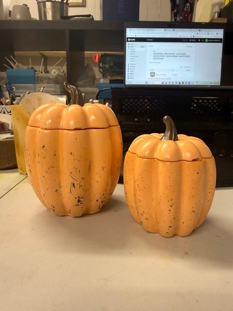 Doodlations Concrete Pumpkin Candle in orange with a black stem. Two sizes shown, with a distressed finish.