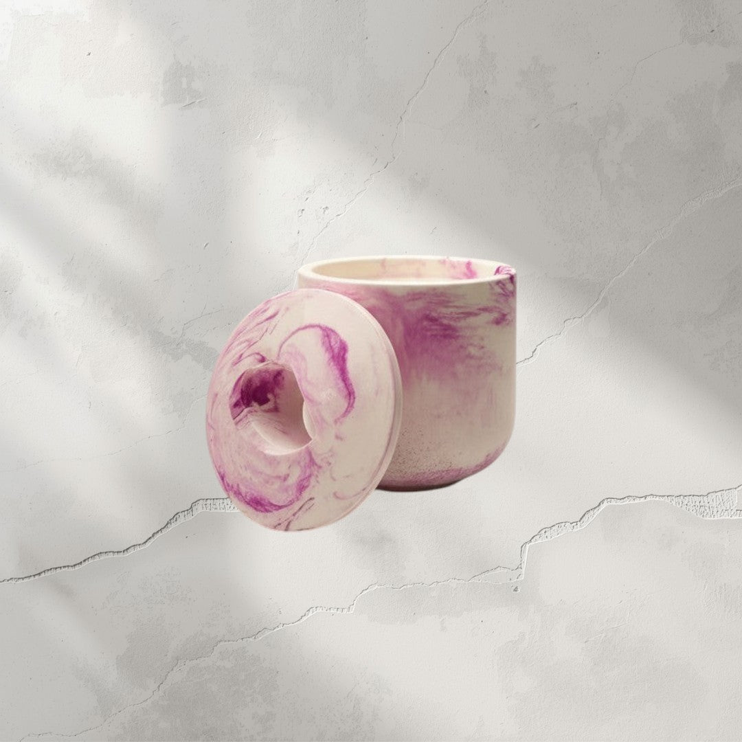 Doodlations Coffee Bar & Boutique marbled pink and white concrete vessel candle with lid.