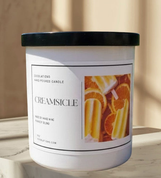 Doodlations hand-poured candle with a creamy orange citrus scent, featuring a label with orange slices and creamsicles.