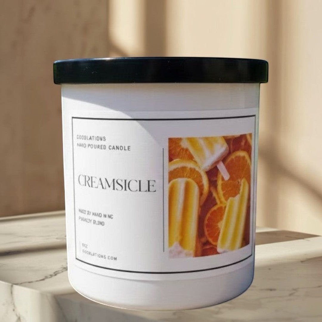 Doodlations hand-poured candle with a creamy orange citrus scent, featuring a label with orange slices and creamsicles.