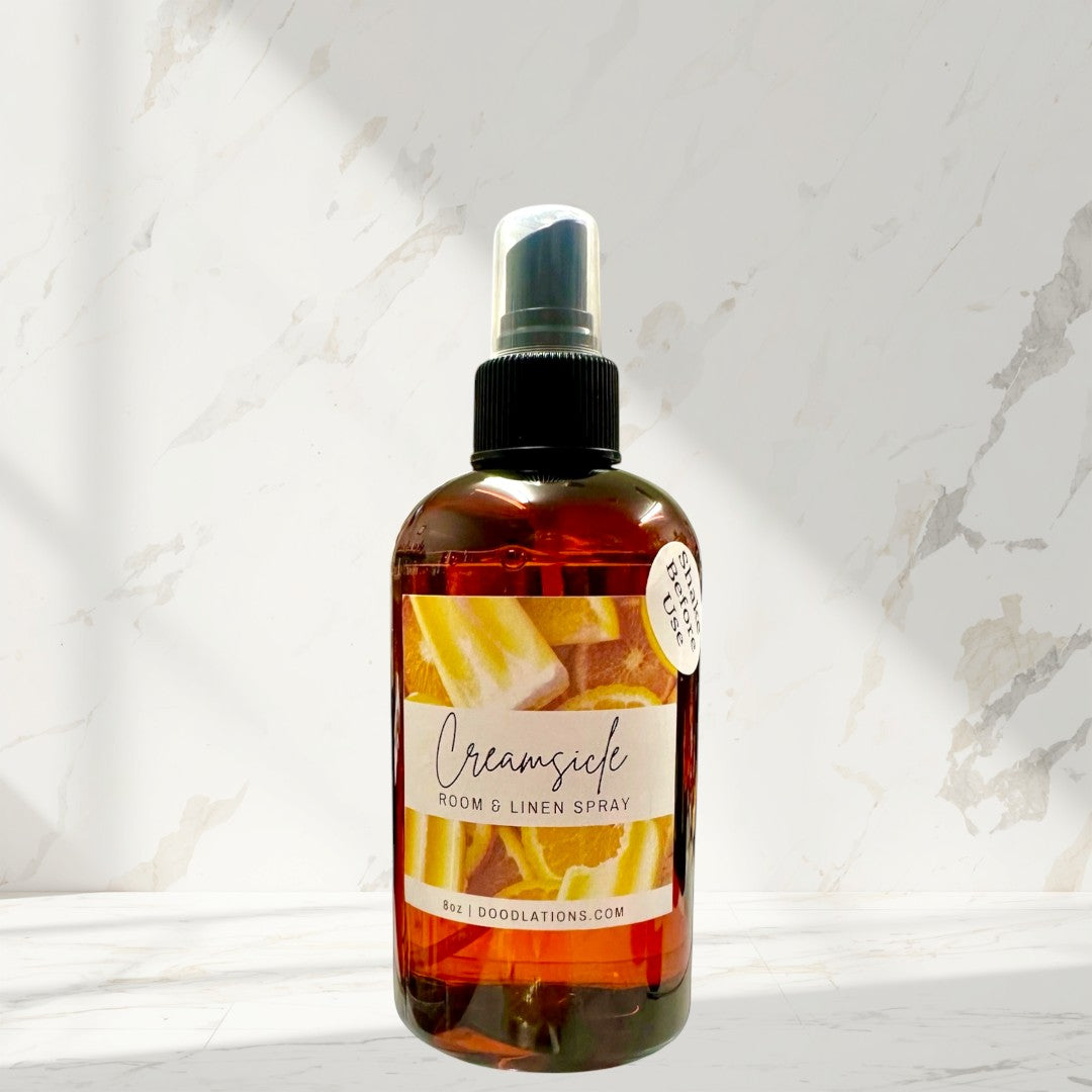 Doodlations Creamsicle room and linen spray in amber bottle with citrus slice label. Refreshing scent.