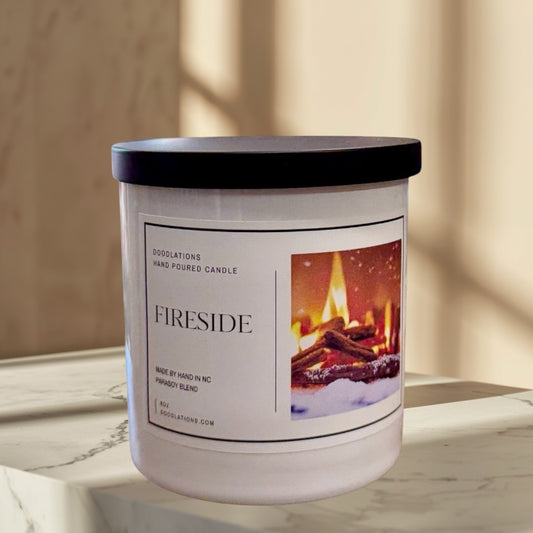 Doodlations Fireside hand-poured candle in a white jar with a black lid, featuring a label with a cozy fireplace image.