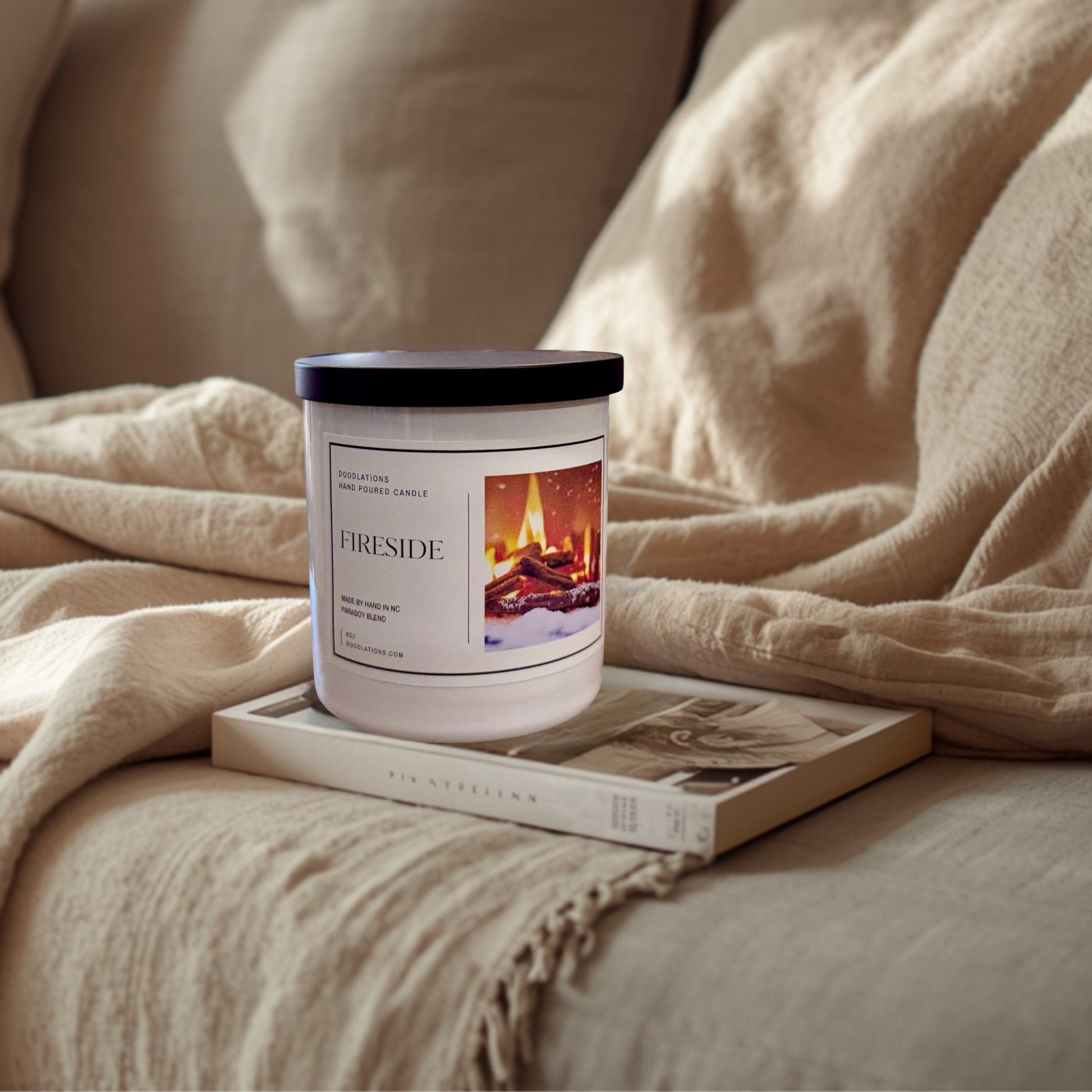 Doodlations Fireside hand-poured soy blend candle with a cozy fireplace graphic. Notes of smoke, wood, clove, amber, sandalwood, and patchouli.