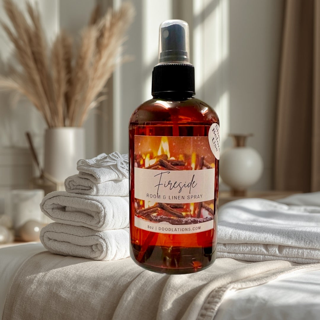 Doodlations Fireside room and linen spray in amber glass bottle with black spray top. Cozy fireplace graphic.