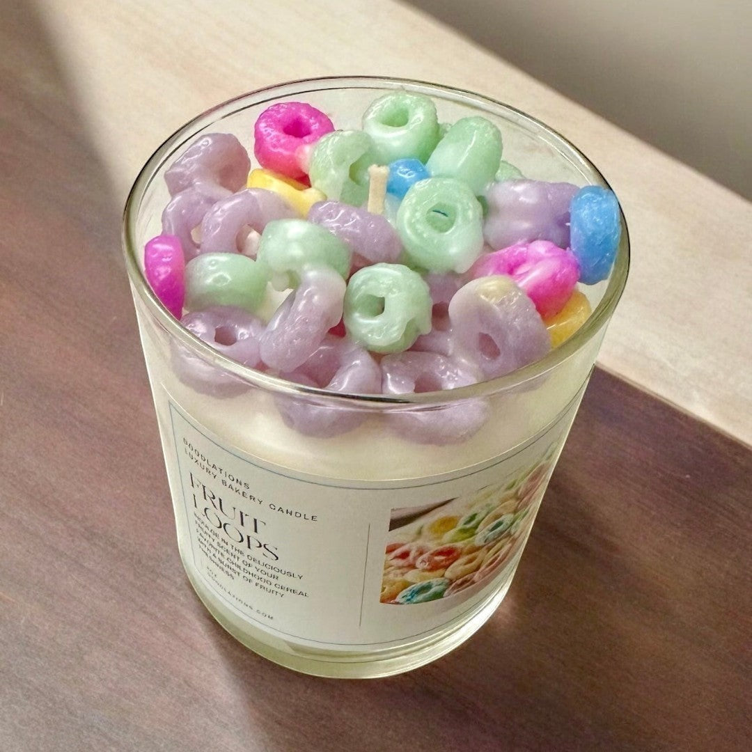 Doodlations Fruit Loop luxury bakery candle in a glass jar, topped with colorful cereal-shaped wax melts.