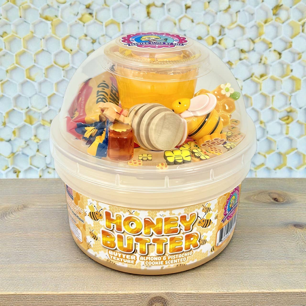 Doodlations Honey Butter Cookie Scented Slime in a clear tub with bee and honey-themed charms. Creamy yellow slime.