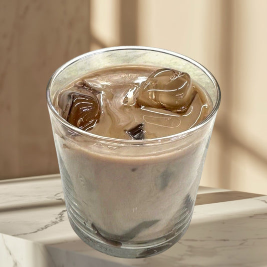 Doodlations Coffee Bar & Boutique iced hazelnut & cream coffee candle in a glass with ice cubes.