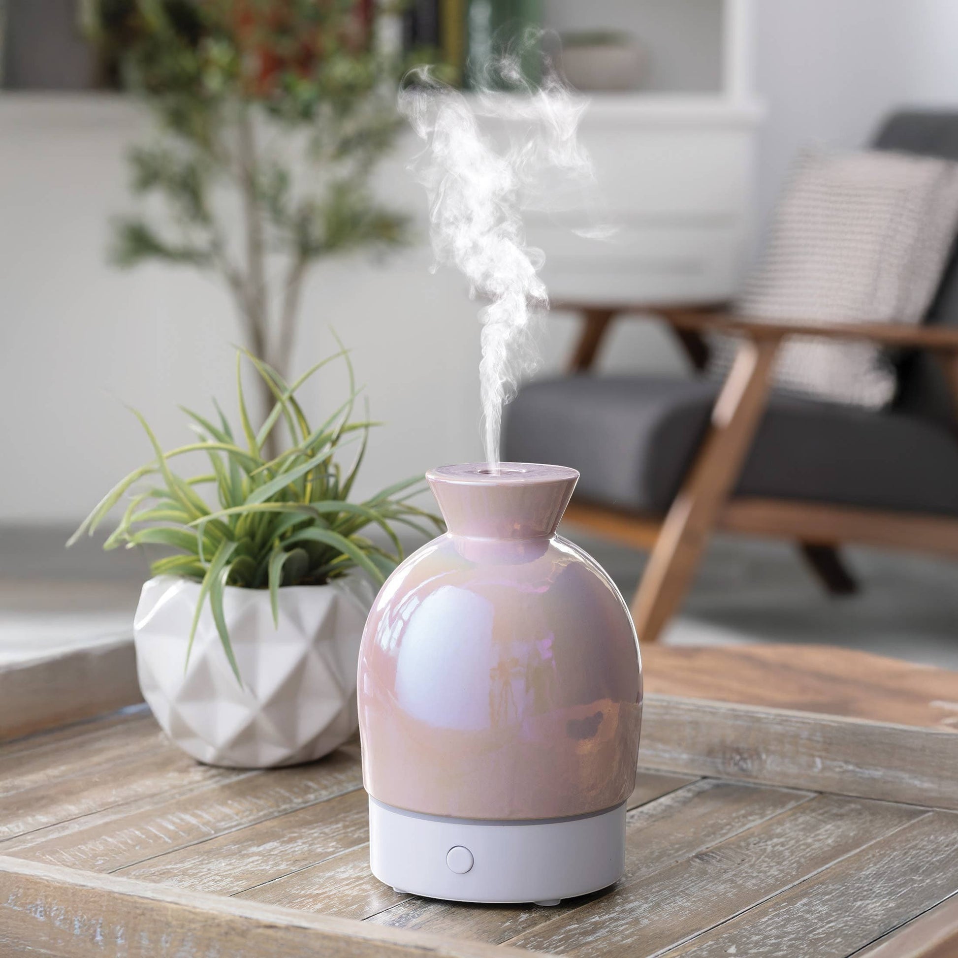Doodlations iridescent water droplet aroma diffuser with pearlescent pink finish emitting mist.