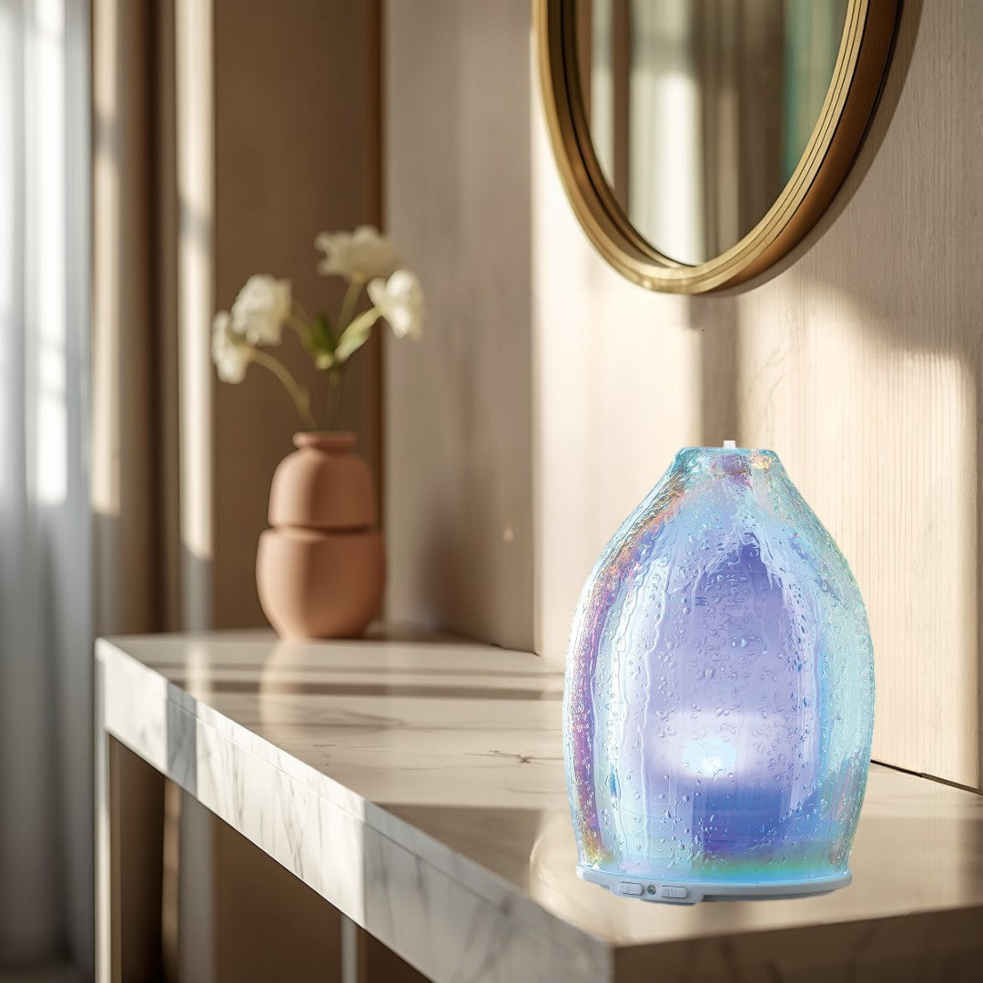 Doodlations iridescent water droplet glass aroma diffuser emitting mist, with purple light.