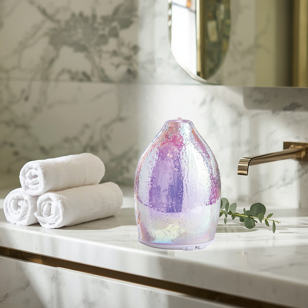 Doodlations iridescent water droplet glass aroma diffuser emitting mist. Textured glass with shimmering rainbow colors.