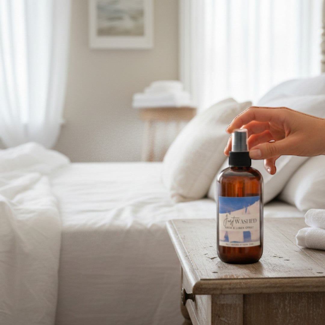 Doodlations Coffee Bar & Boutique Just Washed room and linen spray in amber bottle with blue label, misting in bedroom.