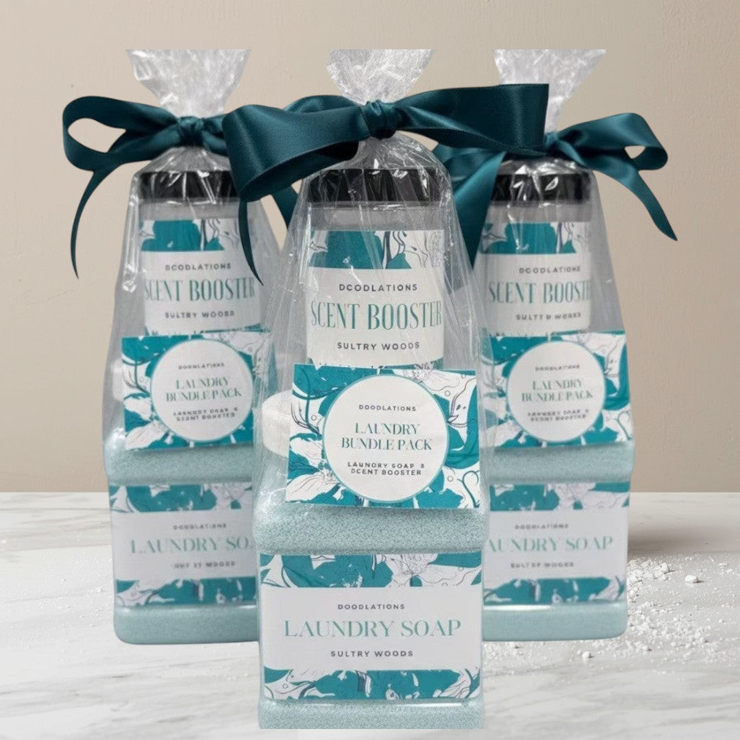 Doodlations Coffee Bar & Boutique Laundry Bundle featuring powdered laundry soap and scent booster in Sultry Woods scent, packaged in clear bottles with teal ribbon.