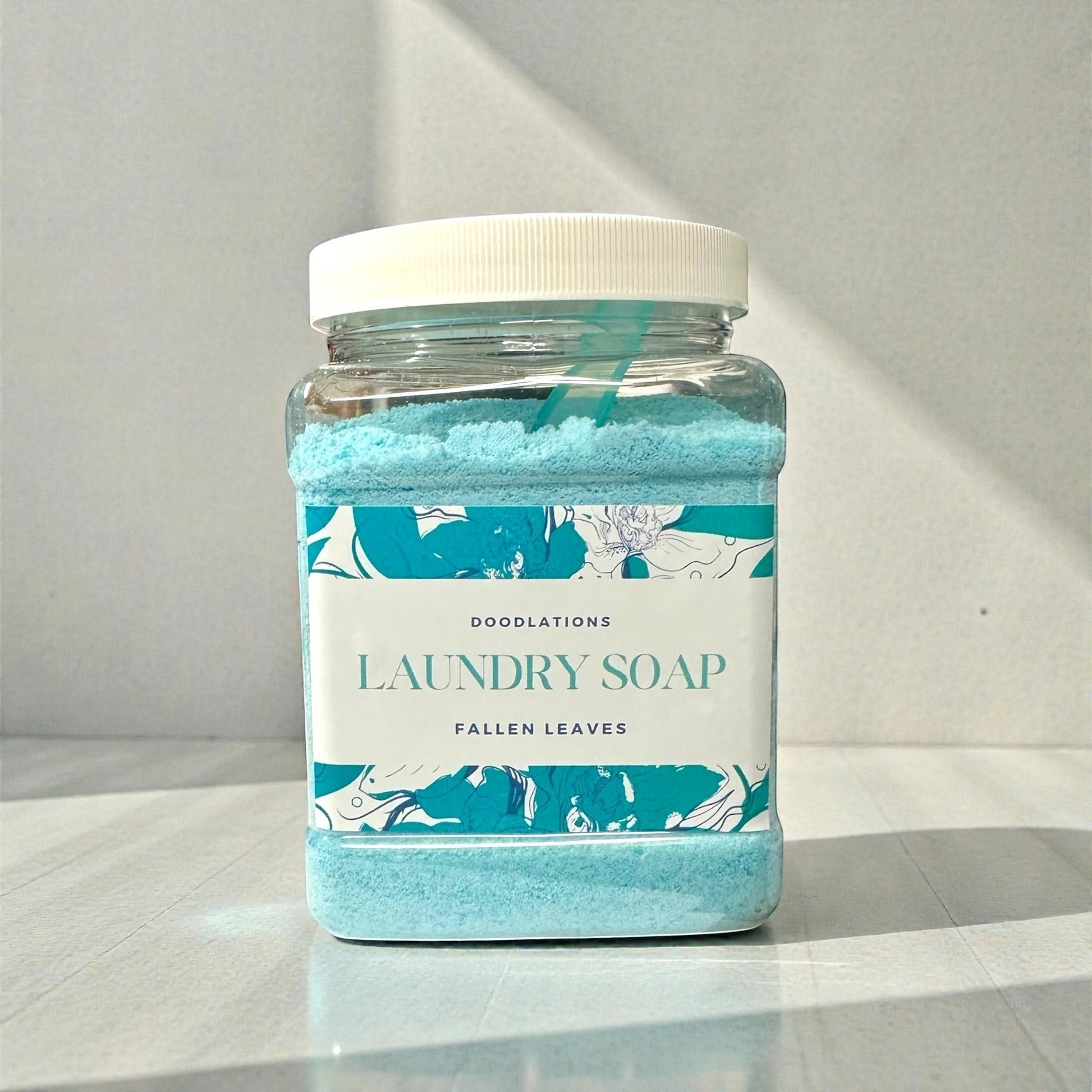 Doodlations Powder Laundry Detergent in Fallen Leaves scent, a bright blue powder in a clear jar with a white lid.