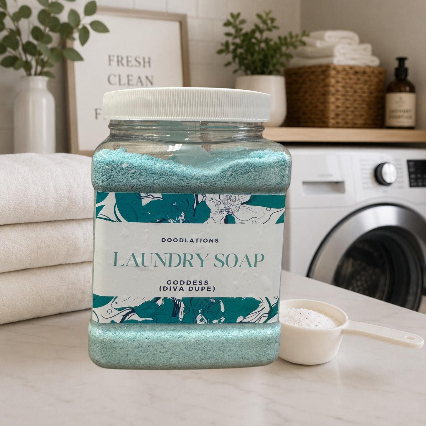 Doodlations Goddess luxury laundry powder in a clear jar with a white lid. Blue powder with floral label.