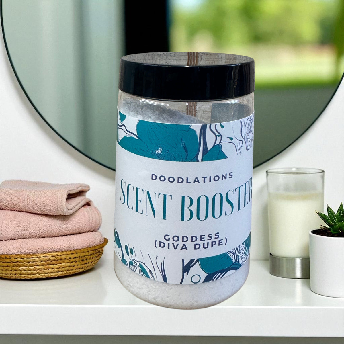 Doodlations Laundry Scent Booster in Goddess scent, a clear jar filled with white beads, on a shelf with pink towels.