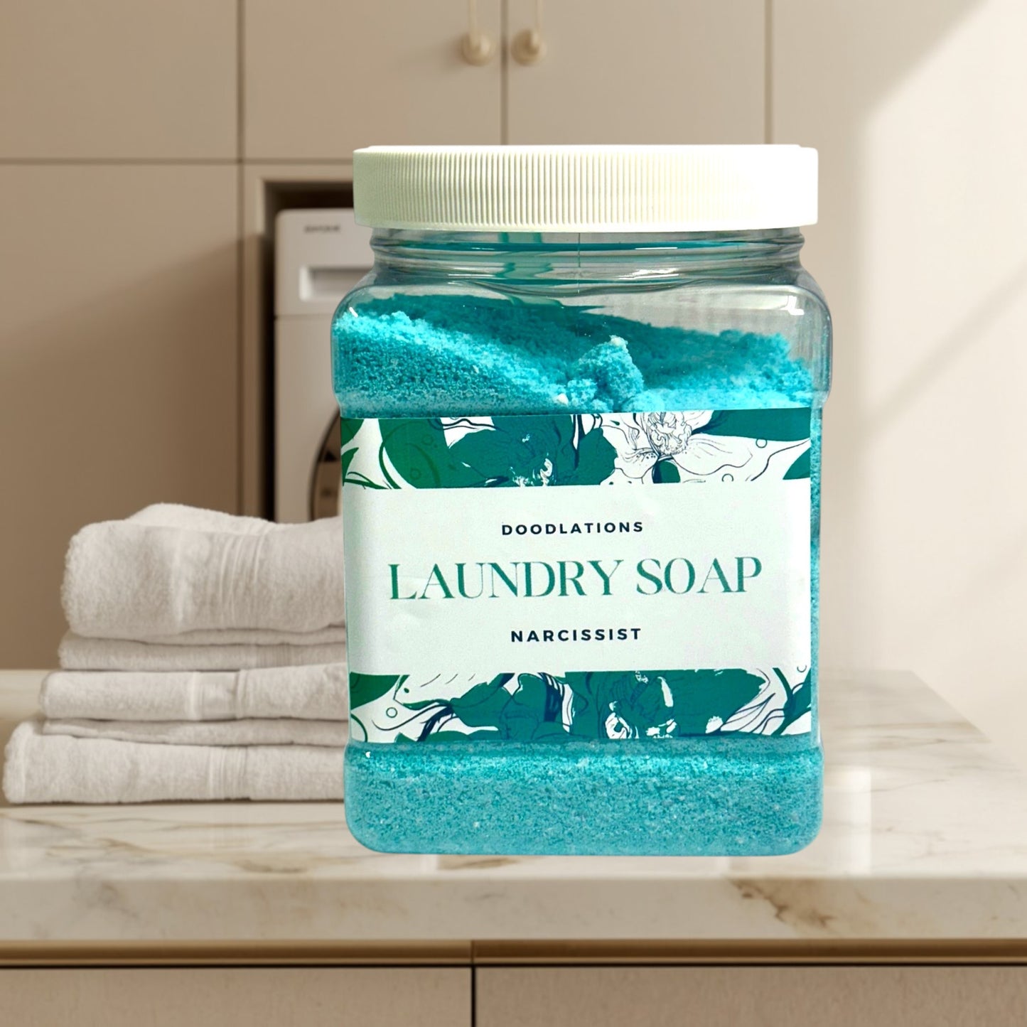Doodlations Narcissist luxury laundry soap powder in a clear jar with a white lid. Blue powder with floral label.