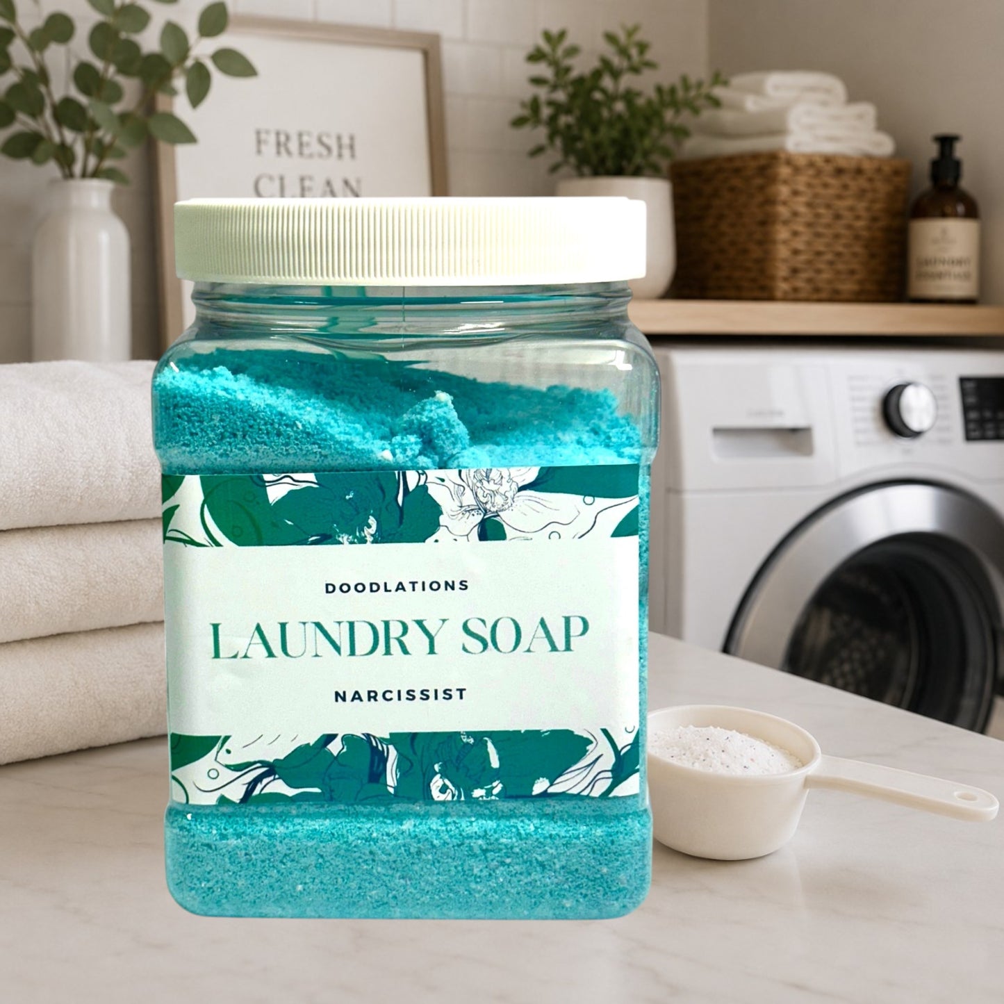 Doodlations Narcissist luxury laundry soap powder in a clear jar with a white lid. The powder is bright turquoise.