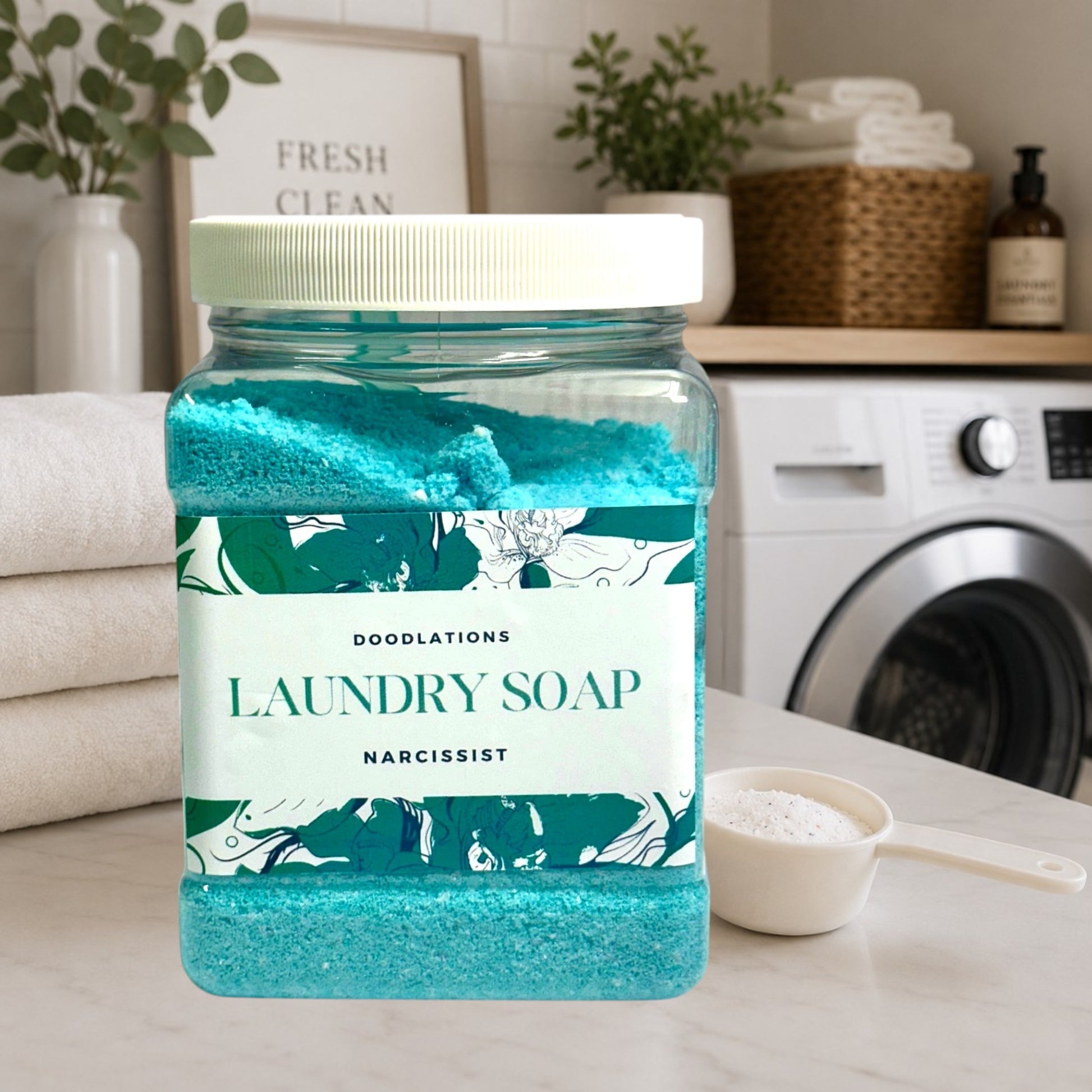 Doodlations Narcissist luxury laundry soap powder in a clear jar with a white lid. The powder is bright turquoise.