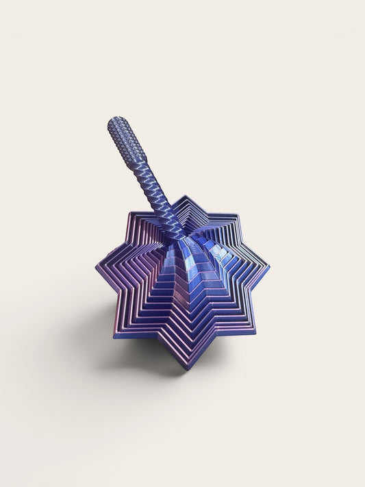 Doodlations Coffee Bar & Boutique Layered Star Fidget Toy in iridescent blue metal with rotating segments for stress relief.