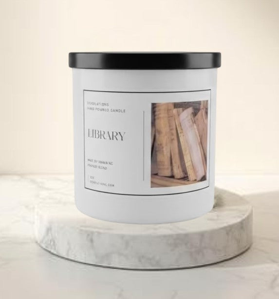 Doodlations Library hand-poured boutique candle with a sophisticated woodsy scent, in a white jar with a black lid.