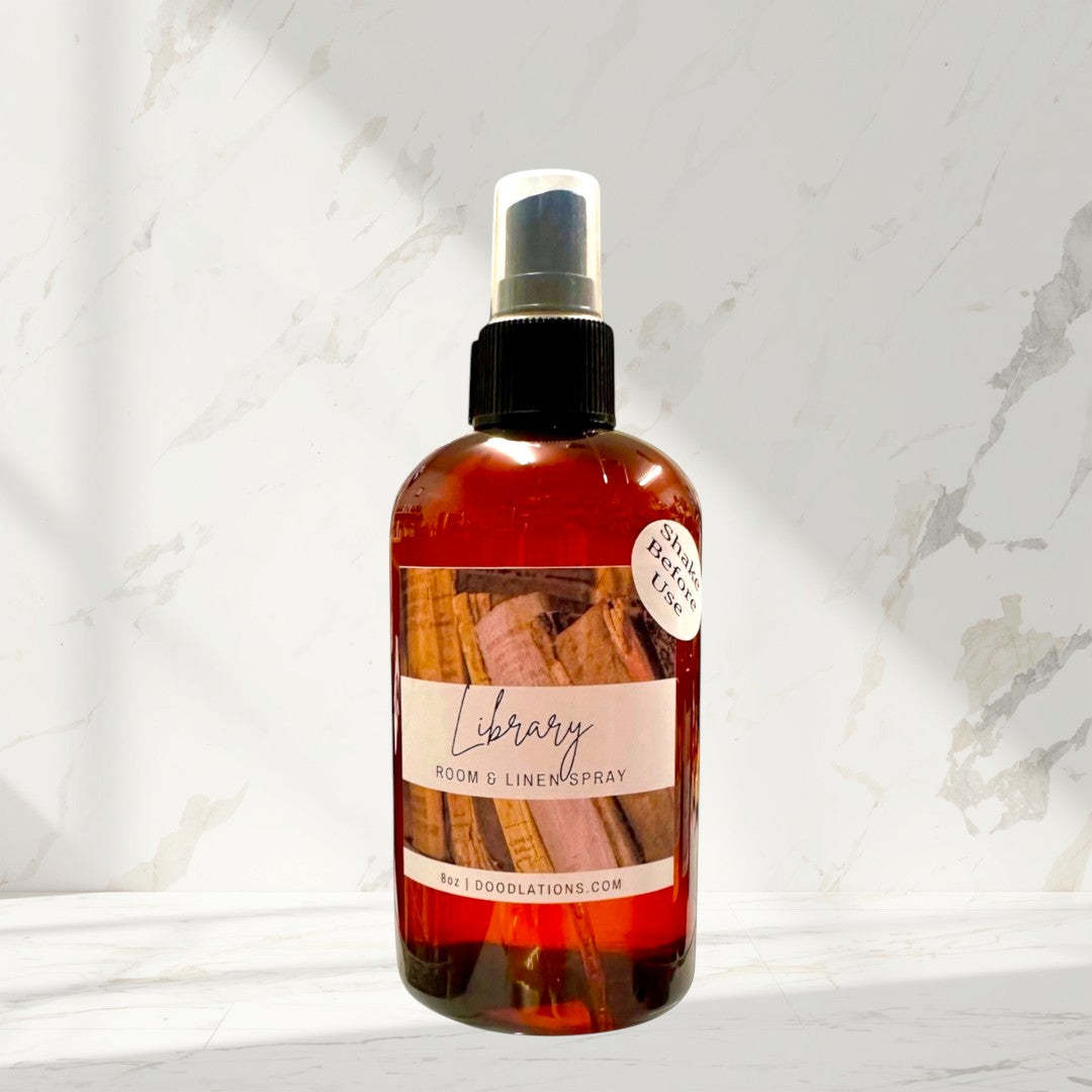 Doodlations Library Room & Linen Spray in amber bottle with black spray top. Scented with teakwood, cedar, leather, sandalwood, musk, and patchouli.