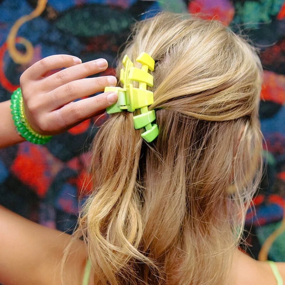 Doodlations Coffee Bar & Boutique lime green gradient segmented claw hair clip holding blonde hair.