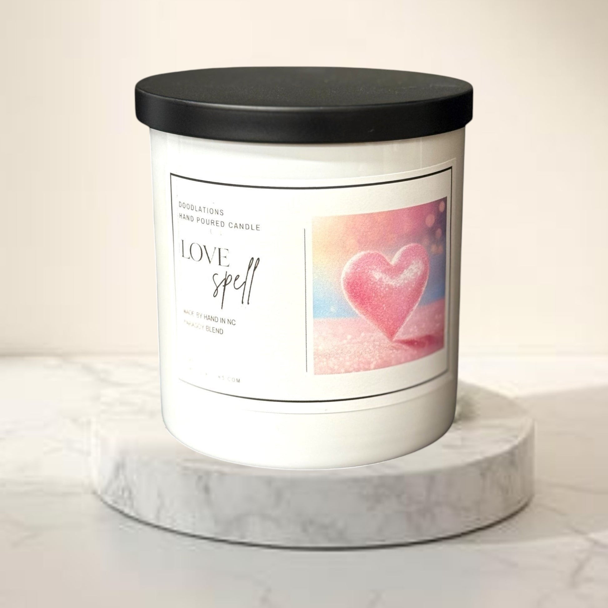 Doodlations Love Spell hand-poured candle in a white jar with a black lid, featuring a pink heart graphic.