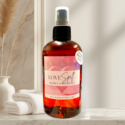 Doodlations Coffee Bar & Boutique Love Spell Room & Linen Spray, 8oz amber glass bottle with spray top. Scent blend of fruit and floral with orange and grapefruit notes.