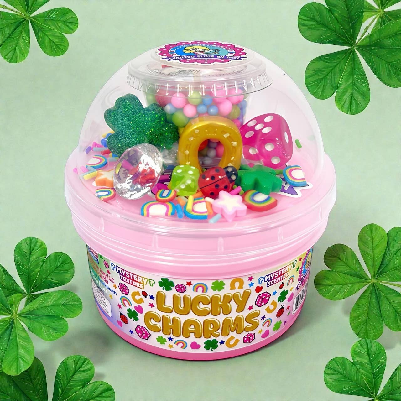 Doodlations Lucky Charms mystery slime in a pink container, filled with colorful charms like dice, ladybugs, horseshoes, and glittery shamrocks.