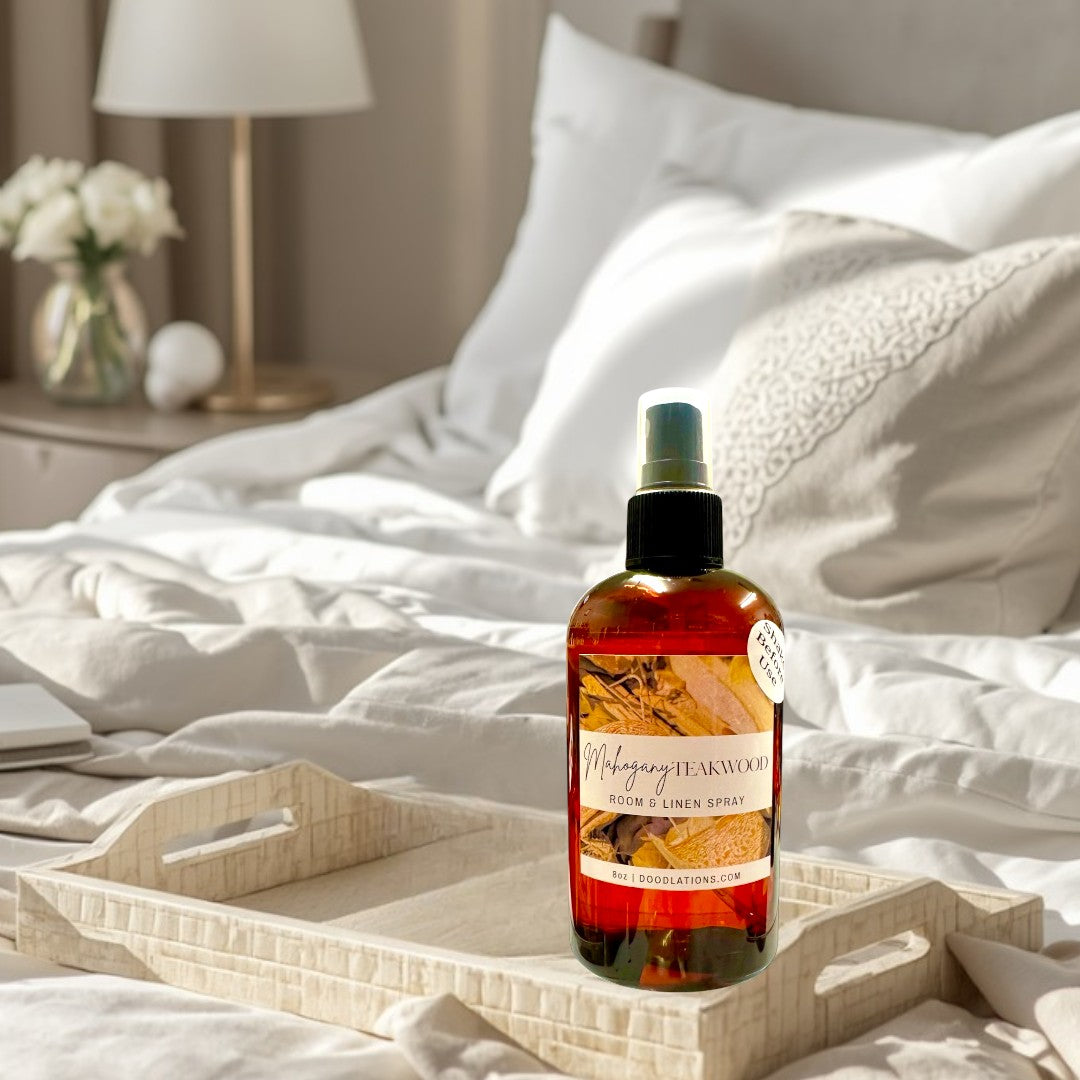 Doodlations Coffee Bar & Boutique Mahogany Teakwood Room & Linen Spray in amber bottle with black spray top.