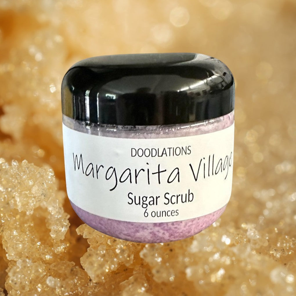 Doodlations Margarita Village sugar scrub in a clear jar with a black lid, featuring a light purple scrub and a white label.