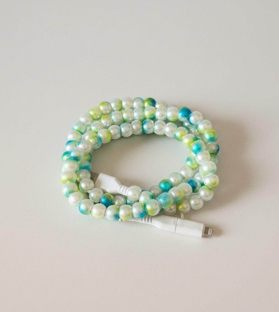 Doodlations Coffee Bar & Boutique mermaid beaded phone charger with white Lightning and USB-C connectors, featuring iridescent pearl beads in green, blue, and white.