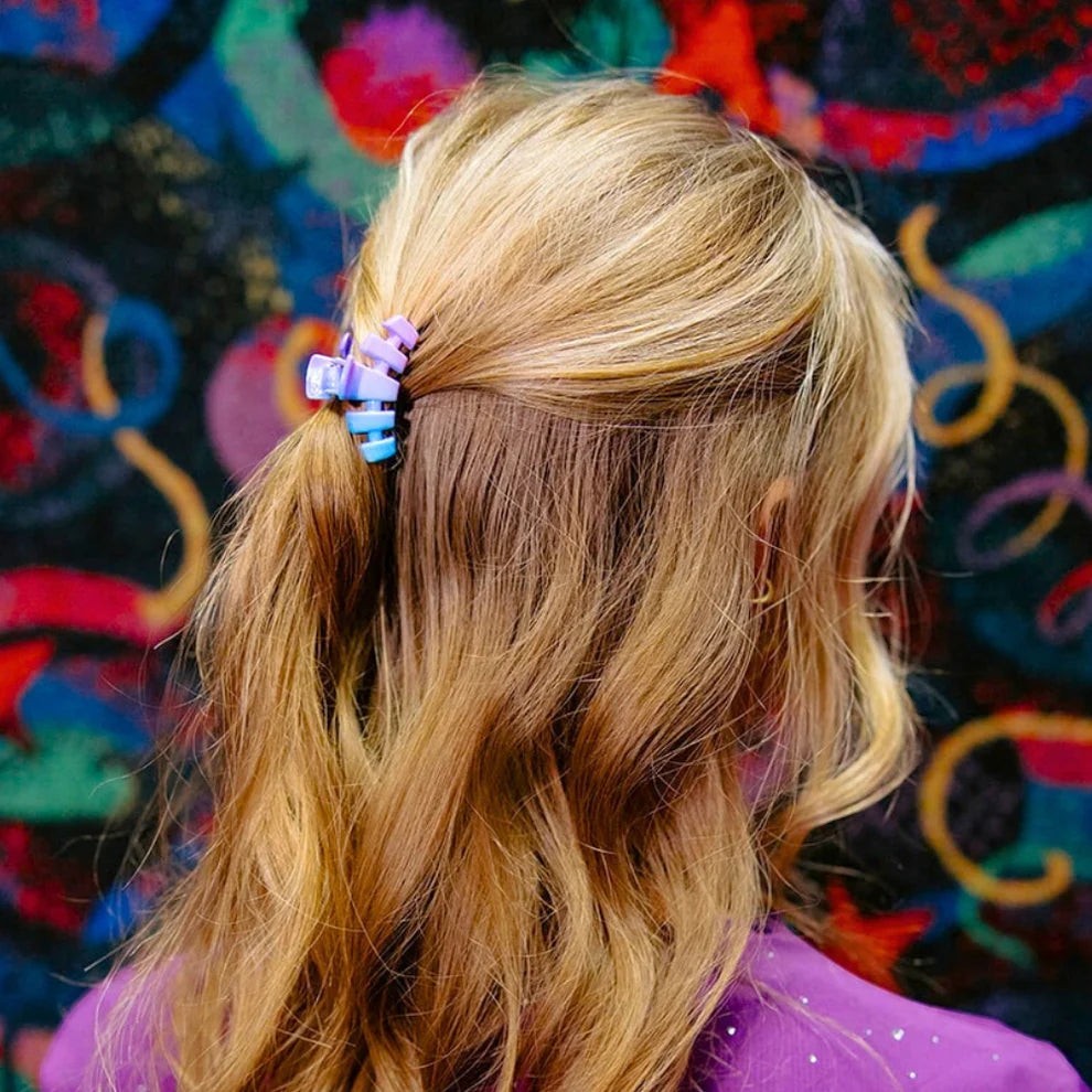 Doodlations Coffee Bar & Boutique Miami Vice claw clip in blue and purple gradient, holding blonde hair in a half-up style.