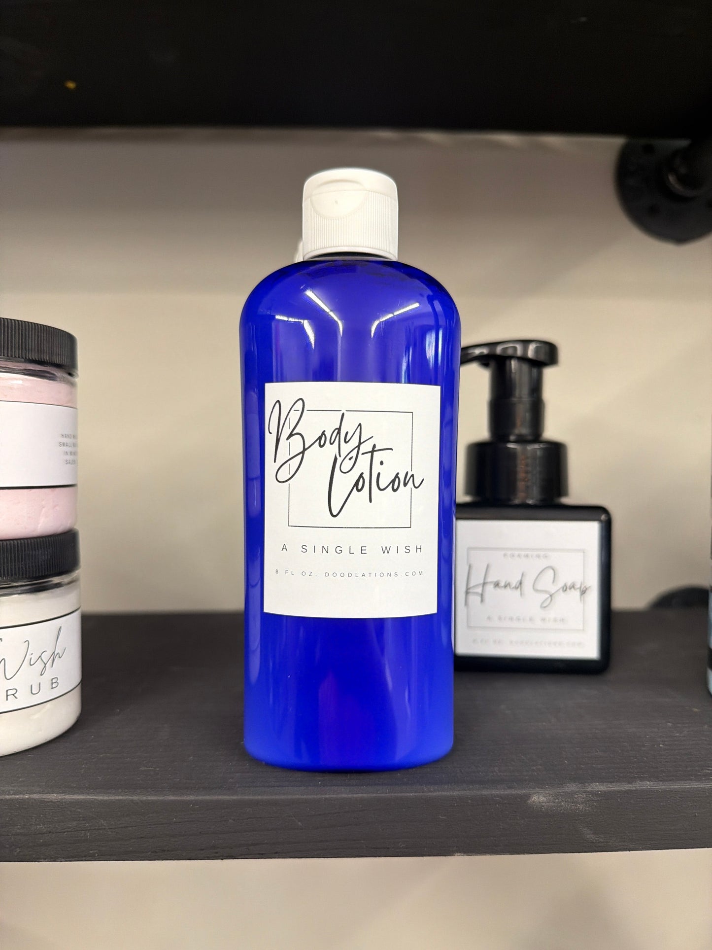 Doodlations Coffee Bar & Boutique blue bottle of moisturizing body lotion, 8oz, with white label.