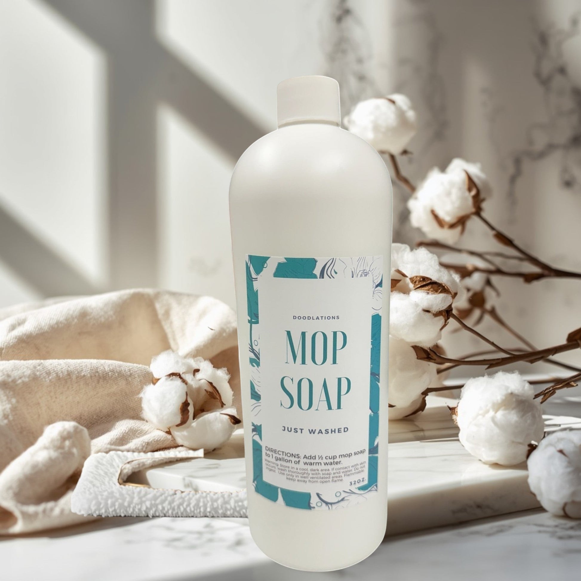Doodlations Mop Soap, concentrated floor cleaner in a white bottle with a teal floral label, next to a gold mop.
