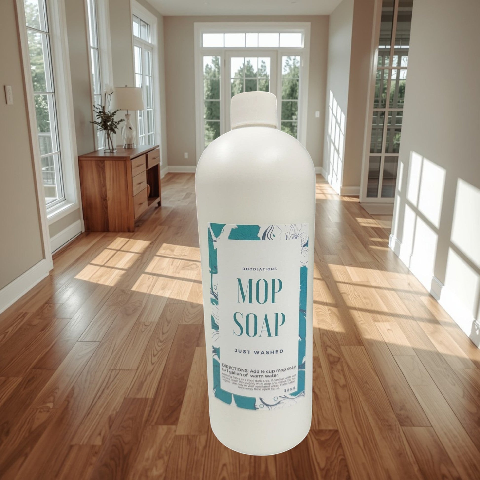 Doodlations Mop Soap, concentrated floor cleaner in a white bottle with a teal floral label, next to a gold mop.