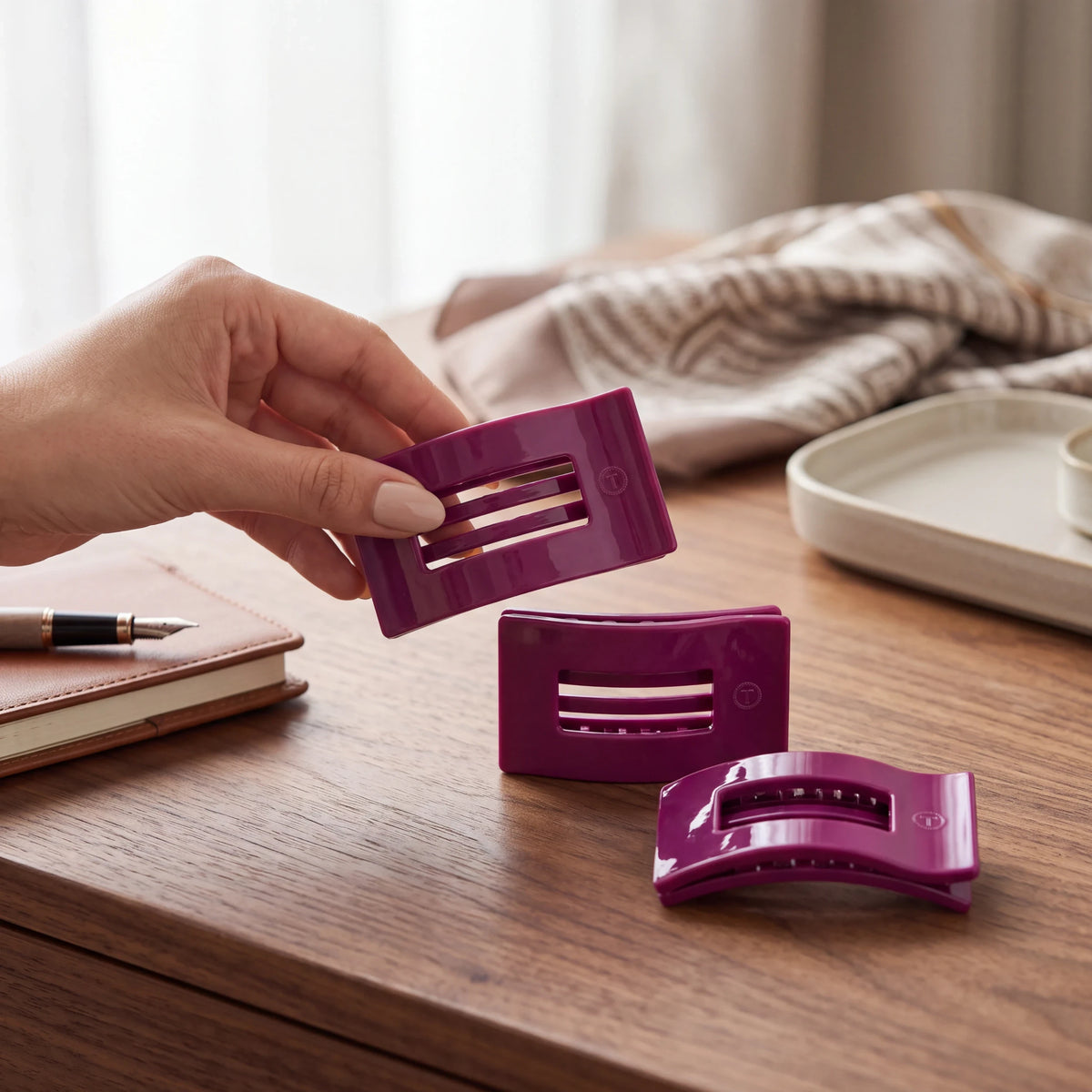 Doodlations Mulberry flat rectangle hair clips in deep berry purple, shown on a wooden desk with a notebook.