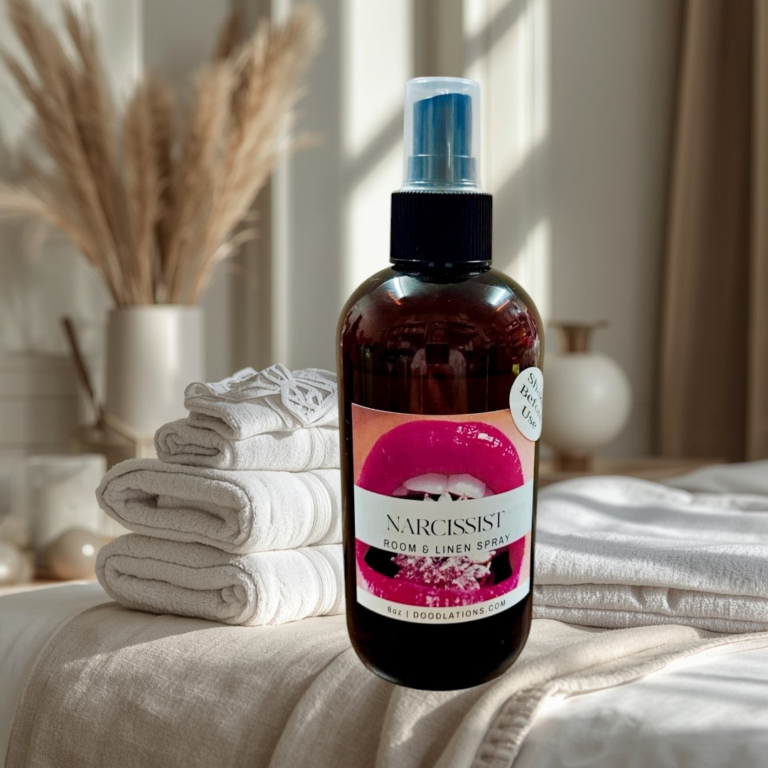 Doodlations Narcissist room & linen spray in amber bottle with a bold fruity-floral scent. Features pink lips graphic.