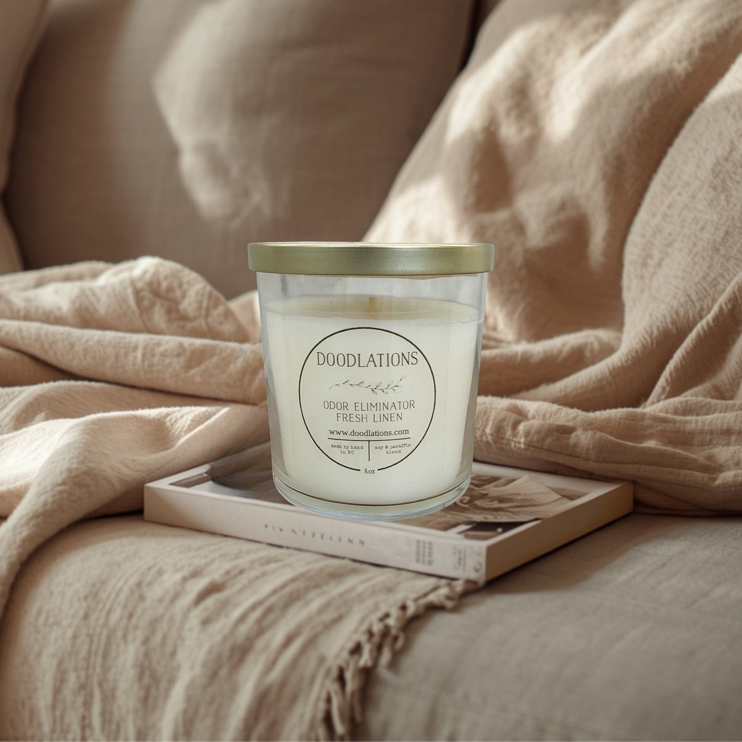 Doodlations Odor Eliminator Fresh Linen candle in a clear glass jar with a gold lid. Soy & paraffin blend.