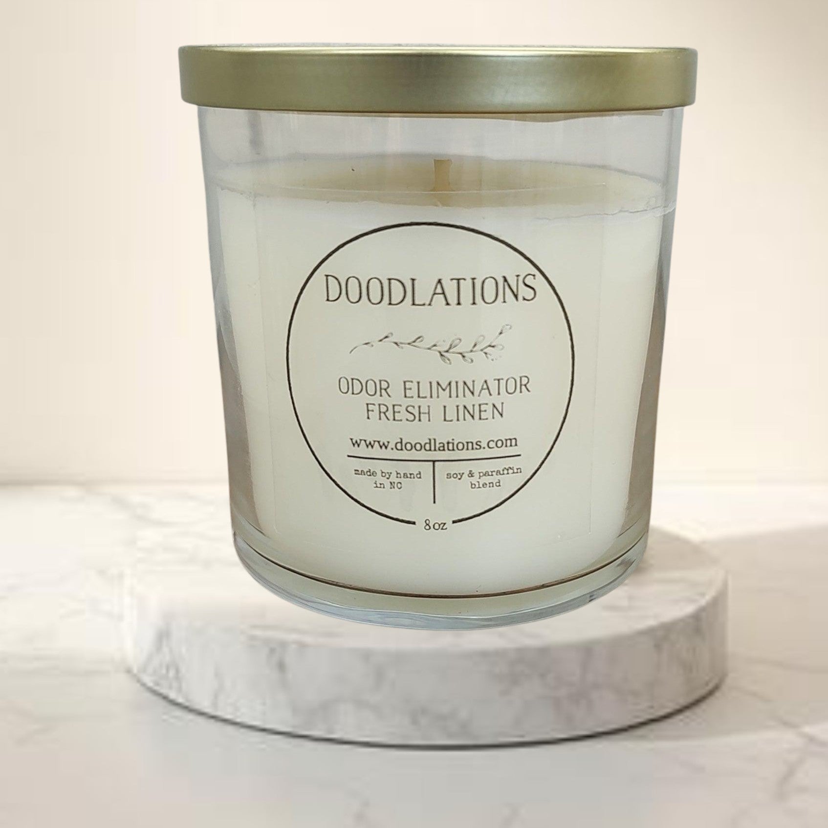 Doodlations Odor Eliminator Fresh Linen candle in a clear glass jar with a gold lid. Soy & paraffin blend.