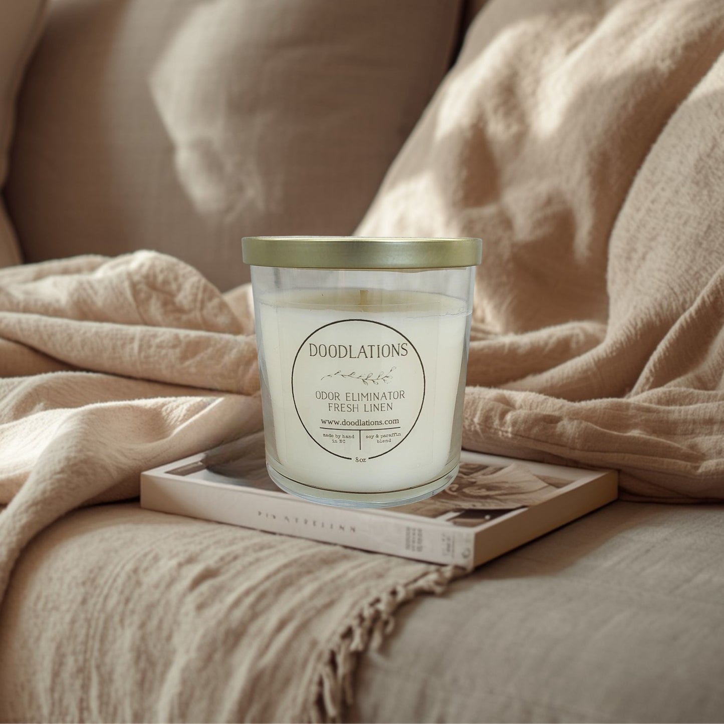 Doodlations Odor Eliminator Fresh Linen candle in a clear glass jar with a gold lid. Soy & paraffin blend.