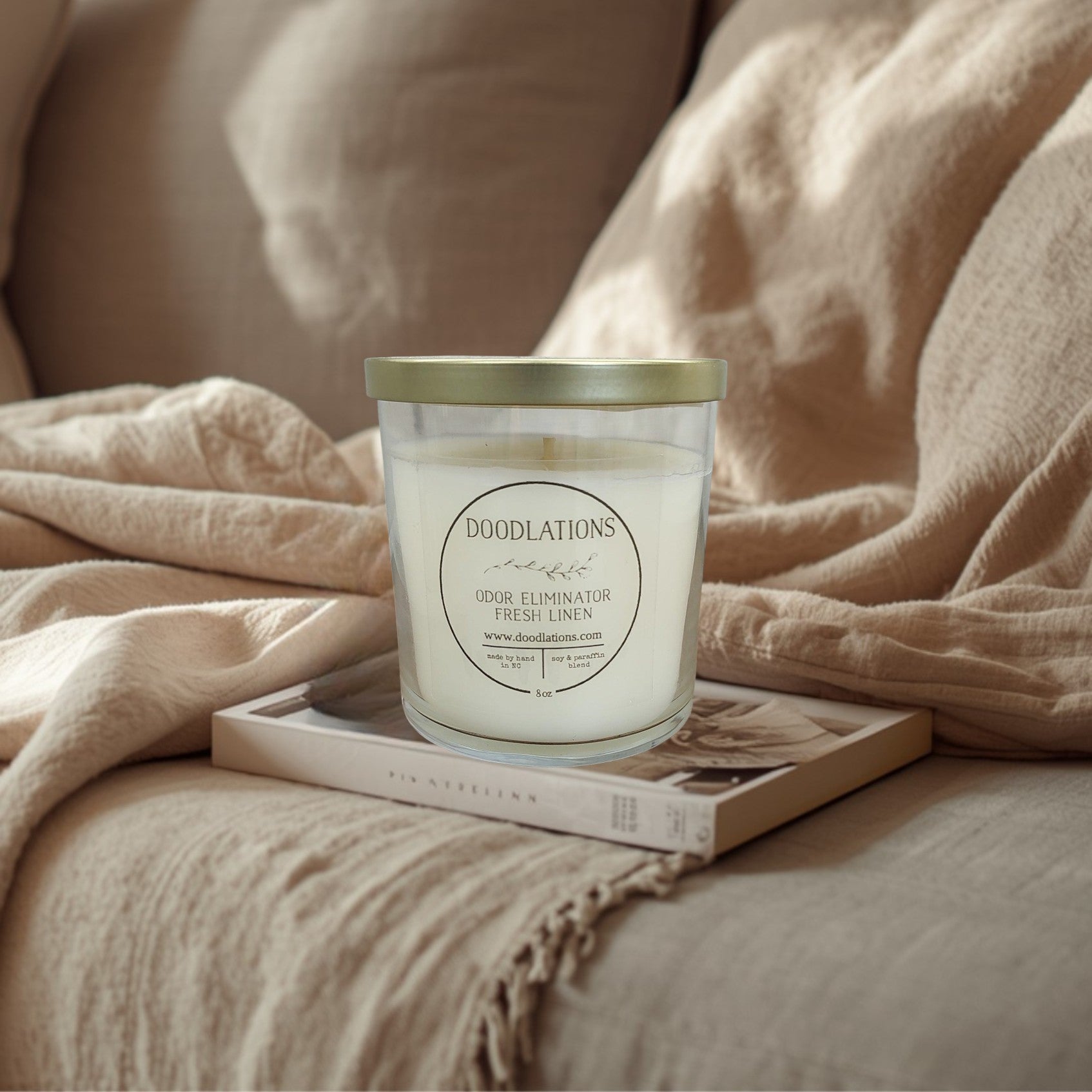 Doodlations Odor Eliminator Fresh Linen candle in a clear glass jar with a gold lid. Soy & paraffin blend.