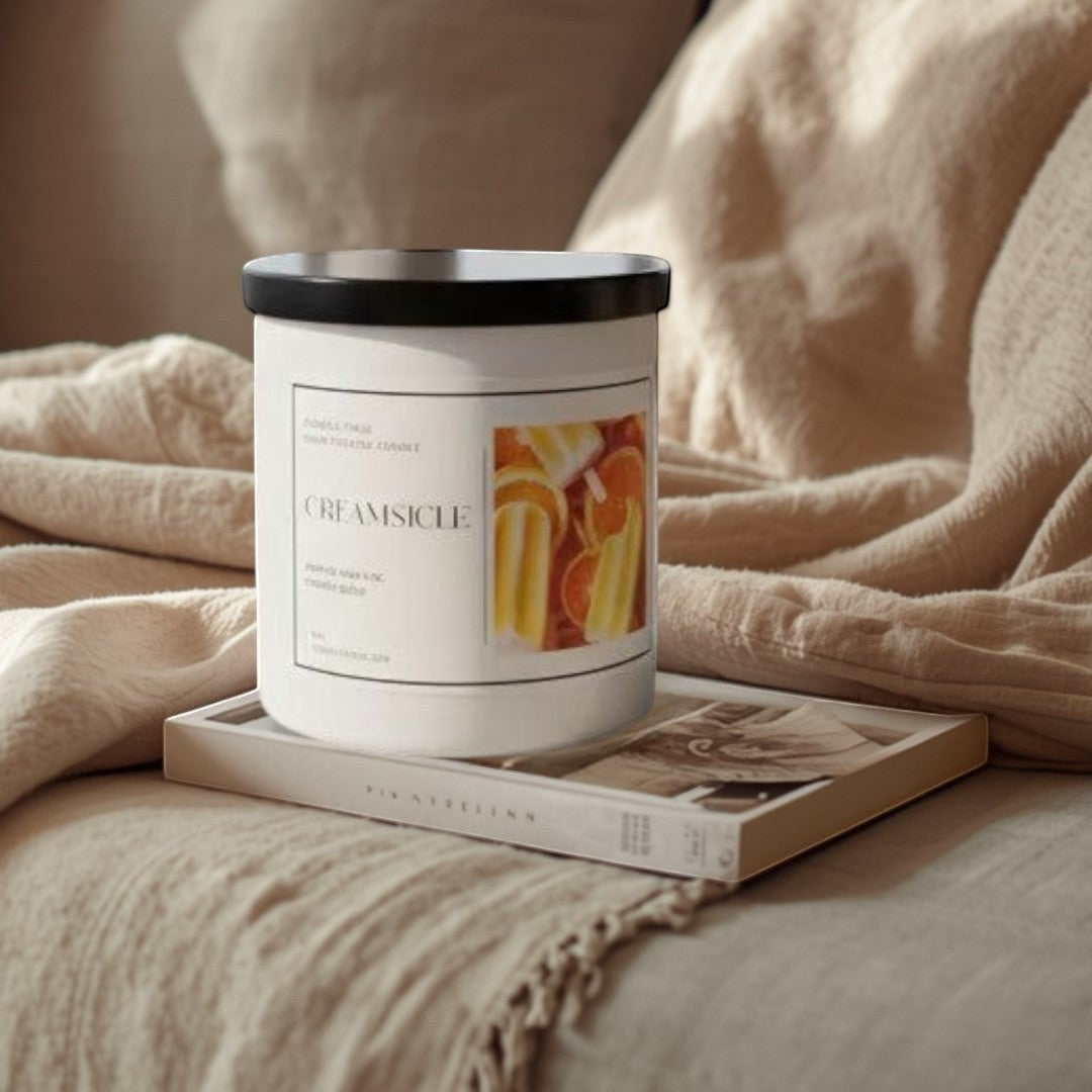 Doodlations Coffee Bar & Boutique Creamy Orange Citrus Candle with vanilla and orange scent, in a white jar with a black lid.